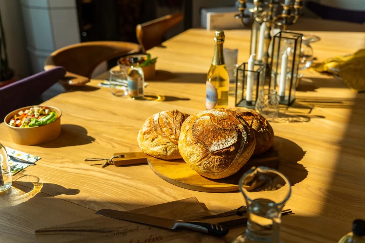 Et langbord dekket med brød, mat og drikke i kveldssol